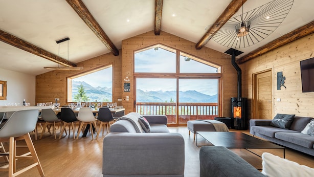 A spacious living area with a large window offering a mountain view, a fireplace, and a modern dining setup.