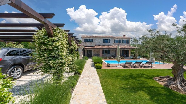 A stone house with a swimming pool, a covered patio, and a car parked in the driveway. - Rustic Villa Noce with pool (Sveti Ivan)