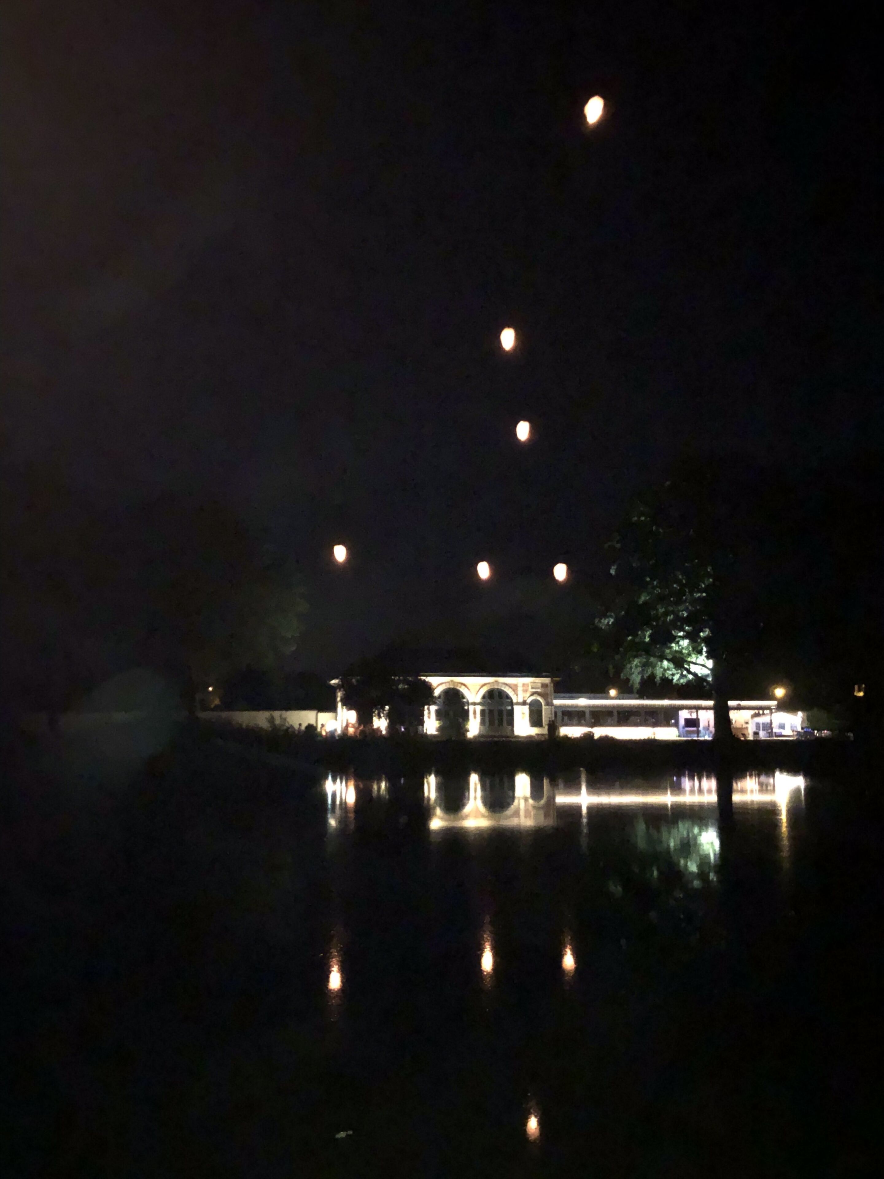 A nighttime view of a building with multiple lights reflecting on the water.