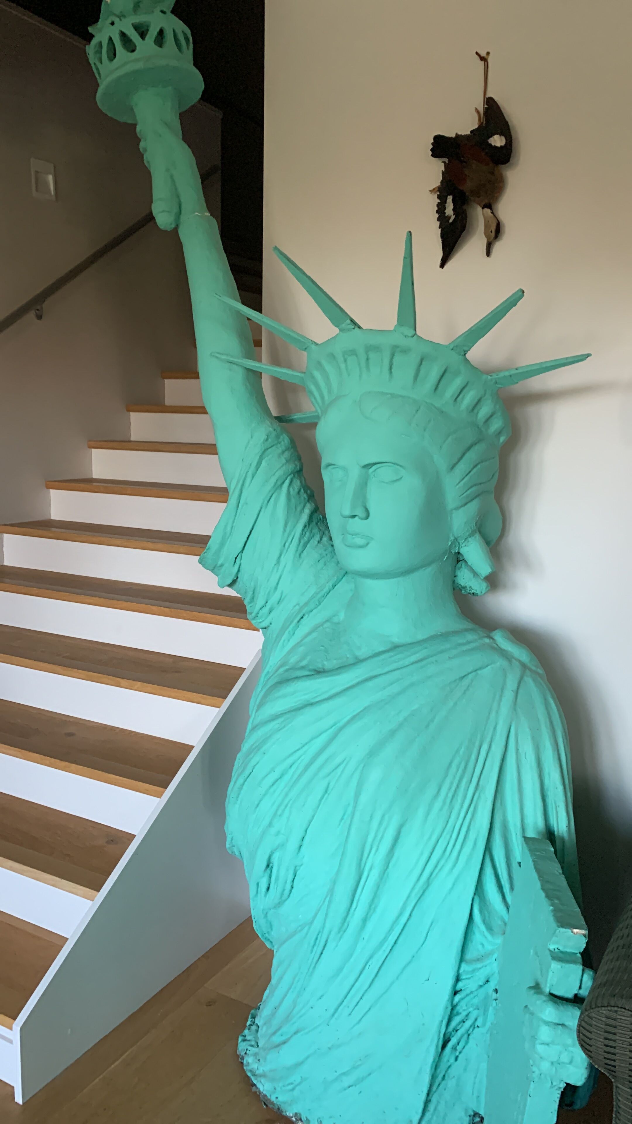 A turquoise statue of the Statue of Liberty in a stairwell.