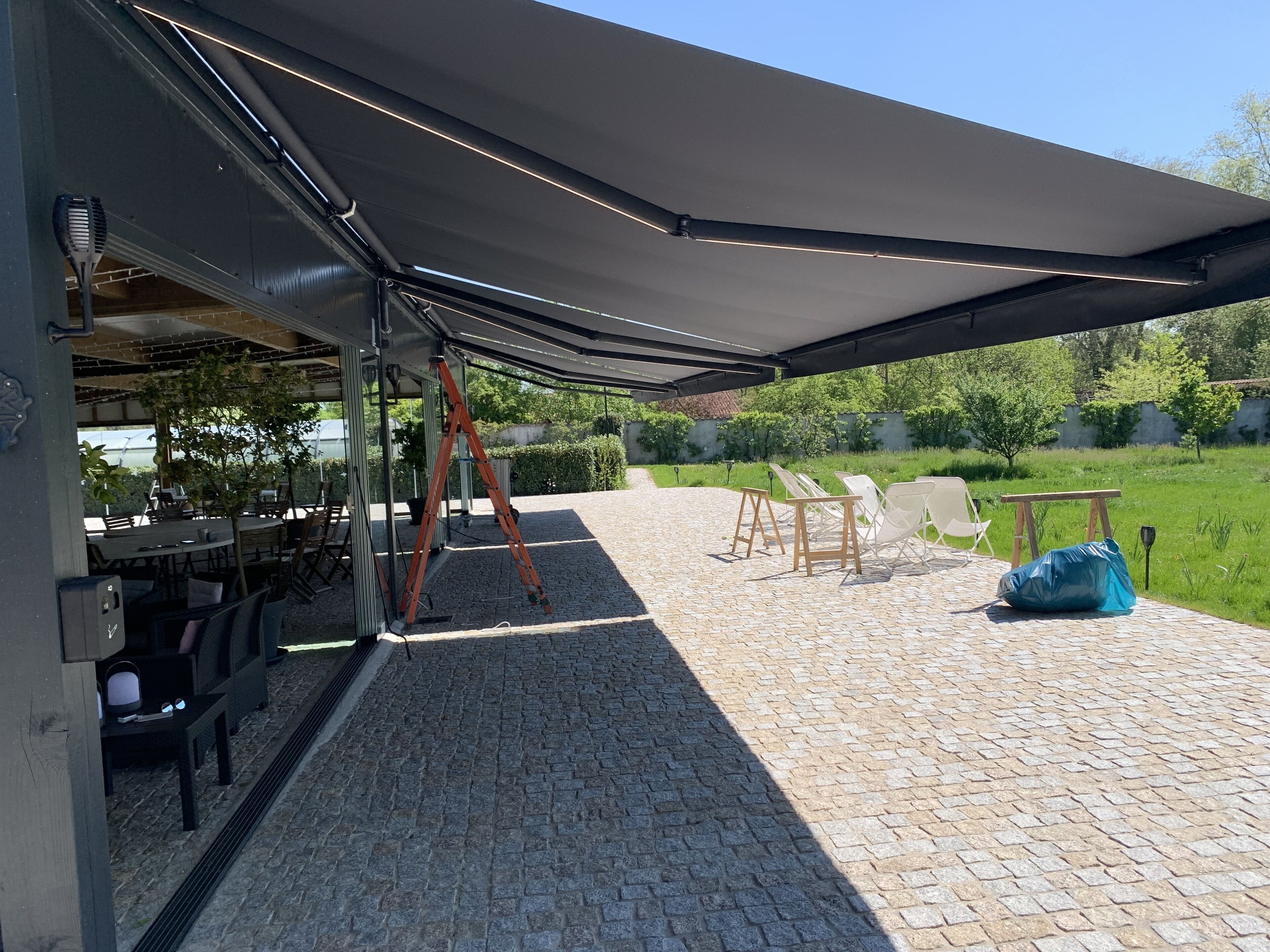 Un patio al aire libre con un espacio de estar techado, una mesa y una escalera.