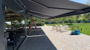 Un patio al aire libre con un espacio de estar techado, una mesa y una escalera.