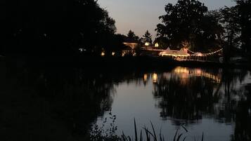 Een nachtzicht van een oever met een gebouw en tenten, verlicht door lichtslingers.