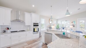 A modern kitchen with white cabinetry, a granite countertop, and stainless steel appliances. - Heated Pool | Game Room | Elevator | Tiki Hut (St. Augustine)