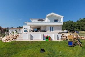 Una casa moderna de dos pisos con balcón, casa de juegos y tobogán.