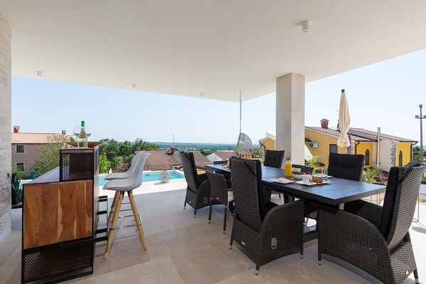 Un patio al aire libre con una mesa de comedor, sillas y una piscina.