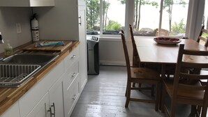Een keuken met witte kastjes, een houten aanrechtblad en een raam met uitzicht op bomen.
