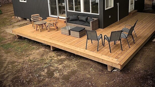 Een klein vakantiehuisje met een terras, een bank en een tafel.