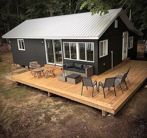 Una cabaña pequeña con terraza, sofá y mesa.