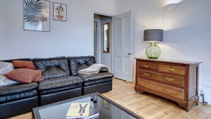 Ein Wohnzimmer mit einem schwarzen Ledersofa, einem Holzschrank und einem Glastisch.