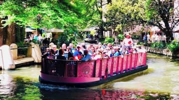 A narrow boat with passengers, surrounded by greenery and water.