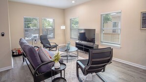 A living room with a sofa, chairs, a TV, and a ceiling fan.
