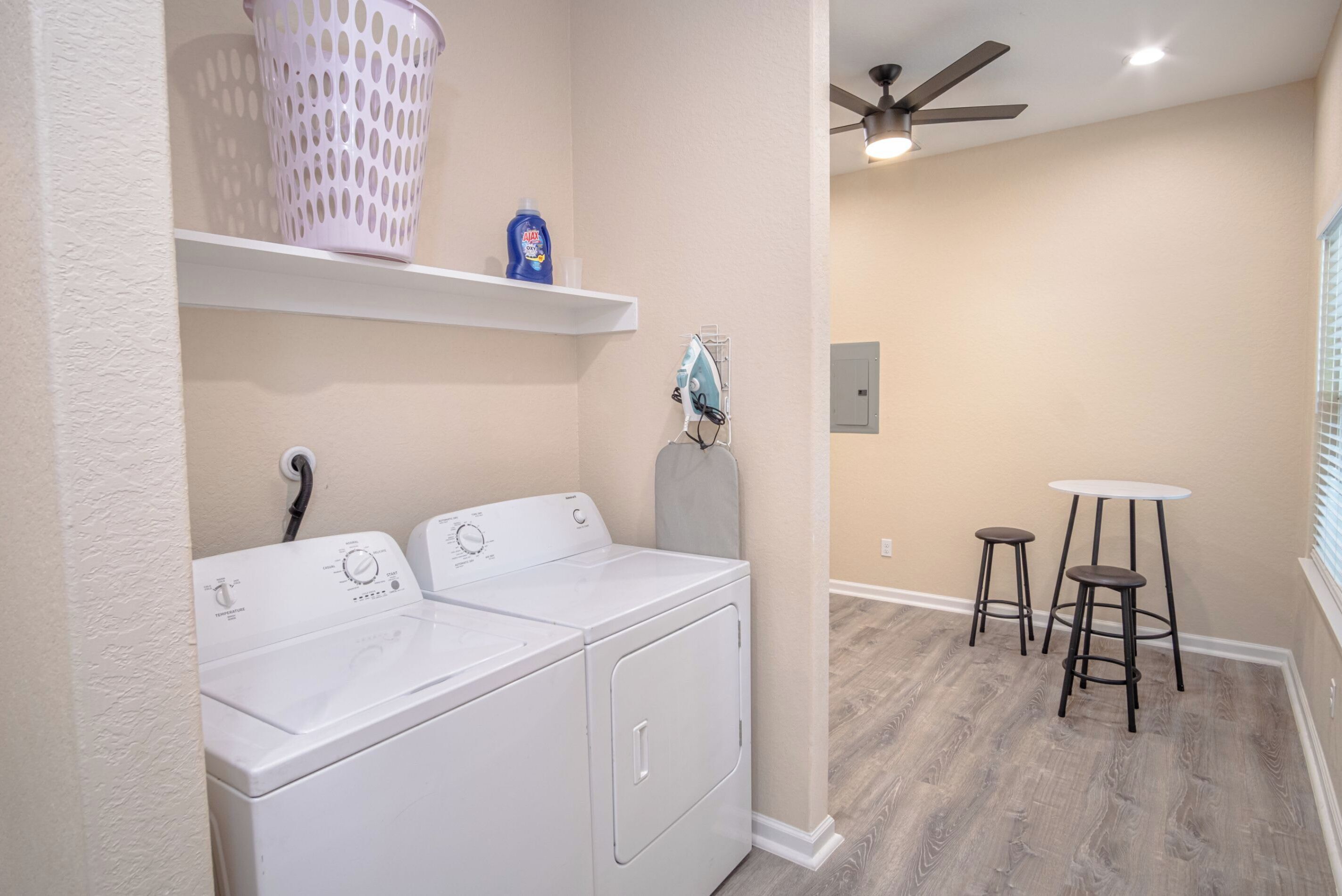 A laundry area with two white front-loading washers, a drying rack, and a ceiling fan.