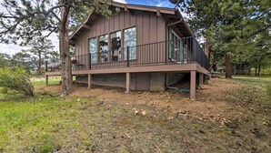Eine zweistöckige Holzhütte mit Balkon, umgeben von Bäumen.