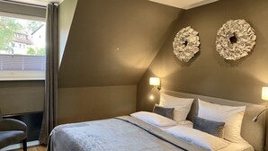 A modern bedroom with a large bed, two wall sconces, and a view of the outside through a window with curtains. - country-apartment XL for 2-4 persons (Braunlage)
