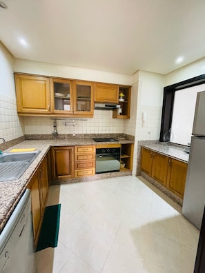 Kitchen features a sink, stove, and microwave, with a window above the sink and tiled walls.
