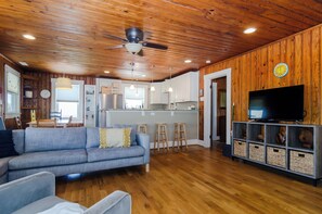 Relax in a comfortable seating area with a sofa and chairs, kitchen with island, and TV on a stand with storage.