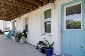 Relax on the covered porch with a comfortable blue chair and potted plants.