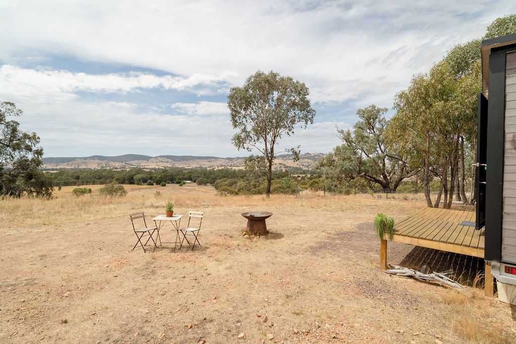 Un'area salotto esterna con tavolo e sedie, un braciere e vista sul paesaggio circostante.