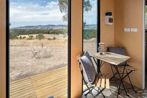Enjoy a serene view of the open landscape from the large window in this compact room with a minimalist design.