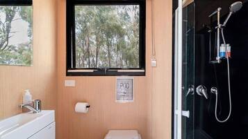 A compact bathroom with a window, a toilet, a sink, and a shower.