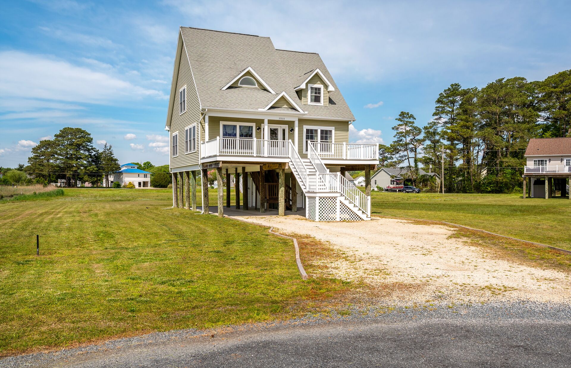 A two-story house with a porch and a covered front porch area, surrounded by a grassy yard and trees.