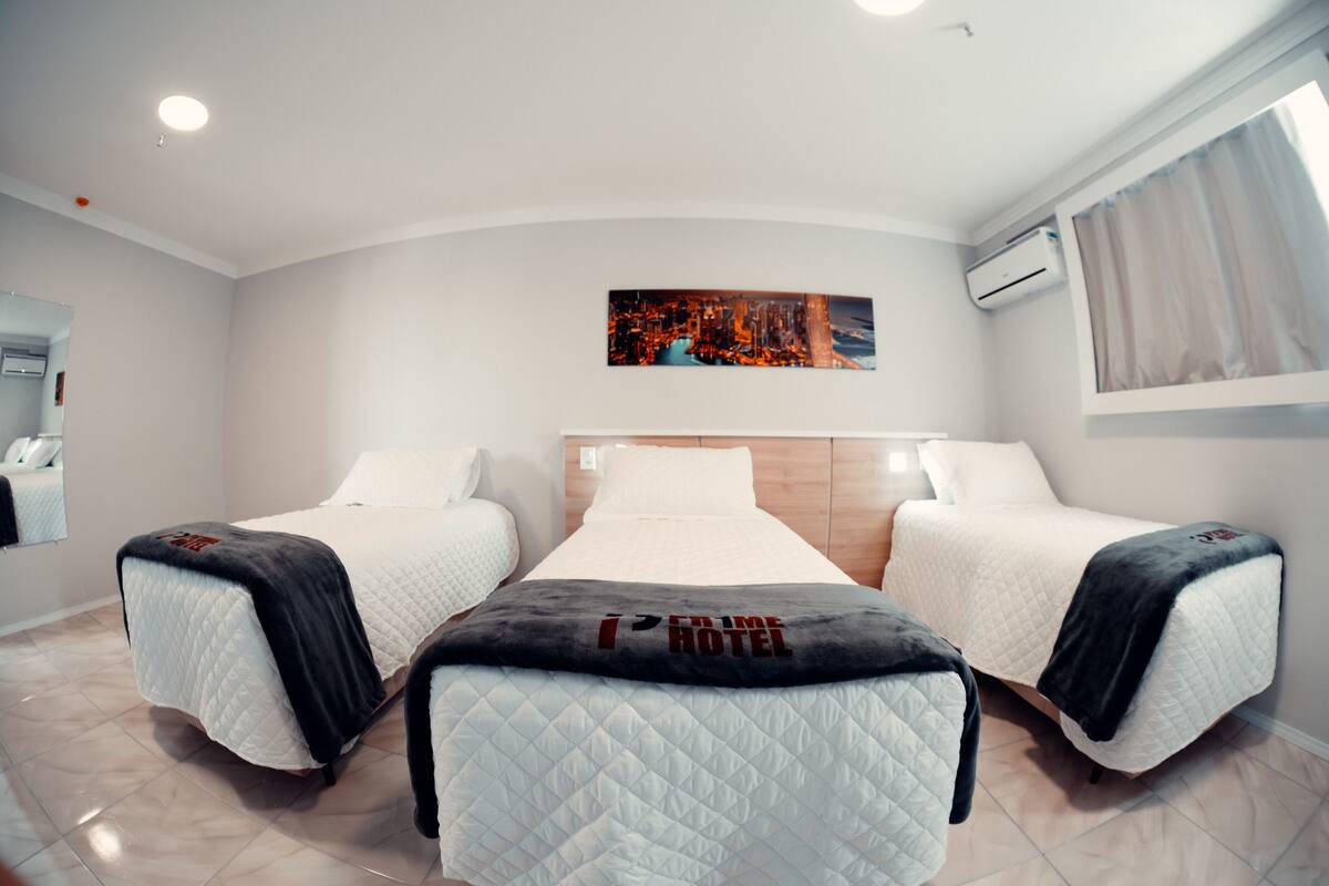 Une chambre d’hôtel avec deux lits, une œuvre d’art représentant un paysage urbain accrochée au mur et un appareil de climatisation.