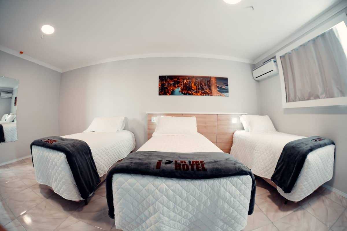 Une chambre d’hôtel avec deux lits, un grand tableau au mur et une fenêtre avec des rideaux.