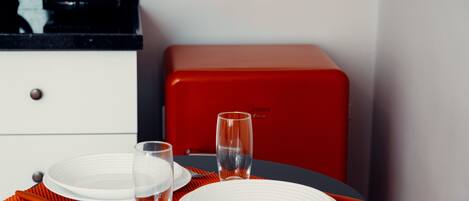 Una mesa de comedor con platos blancos, dos vasos y un tapete rojo.