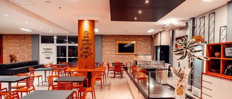 A modern cafe with wooden accents, a brick wall, and a TV mounted on the wall.