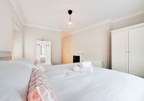 Relax in a serene space with a large bed, wardrobe, and fireplace.