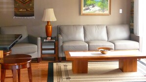 A living room with a sofa, coffee table, and a lamp. There is a painting on the wall and a rug on the floor.