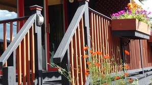A wooden deck with a red-framed door and a planter box with flowers.