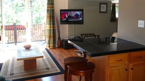 A kitchen with a TV, wooden cabinets, a chandelier, and a dining area with a table and chairs.