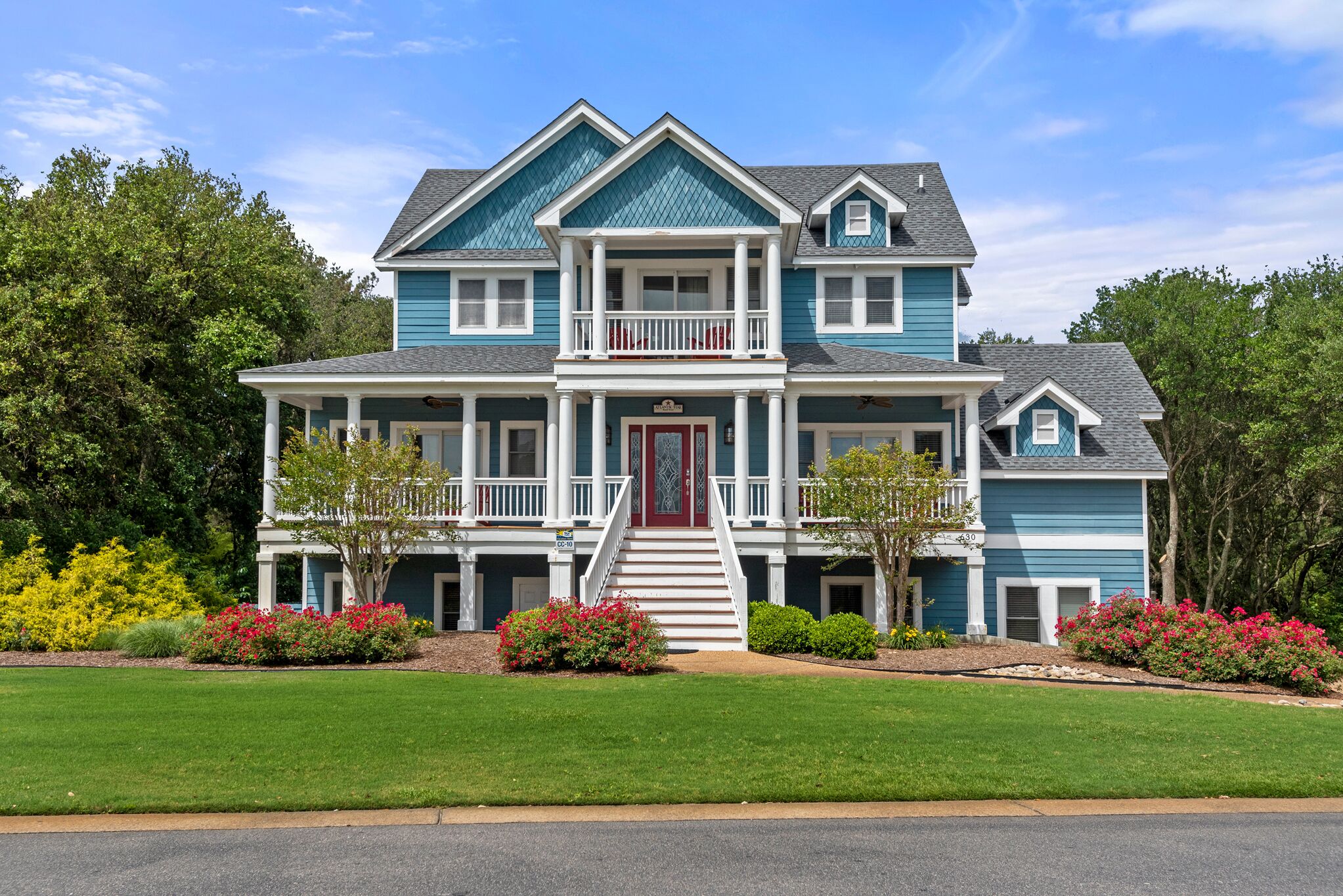 A two-story house with a front porch, a red door, and a small balcony.