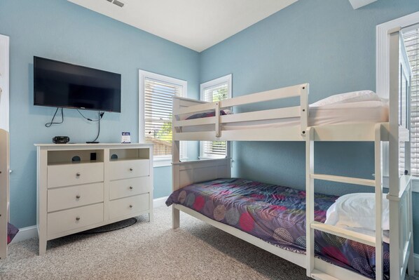 A bunk bed with a TV above it, a dresser, and windows with blinds. - Atlantic Star: Pool, Hot Tub, Rec Room, Theater Room (Corolla)
