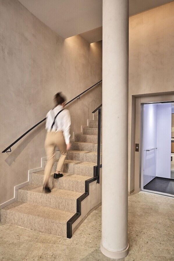 A modern interior with a staircase, a large column, and a door leading to another room. - Joe´s Gomila Boutique Hotel (Palma)