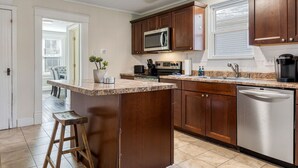 Una cocina con armarios de madera, lavavajillas de acero inoxidable, microondas y cafetera.