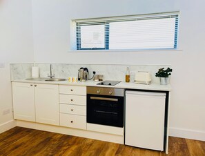 Eine kompakte Küche mit Spüle, Herd und Geschirrspüler, mit einem Fenster über der Spüle.