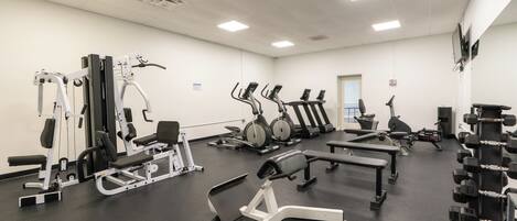 A gym with various exercise equipment, including treadmills, stationary bikes, and weight machines.