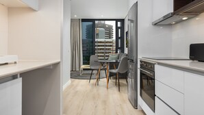 Une cuisine moderne avec des meubles blancs, un four encastré et un coin repas comprenant une table et des chaises.