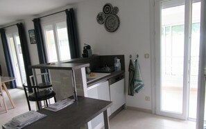 A kitchen with a dining table, chairs, a sink, and a window with curtains.
