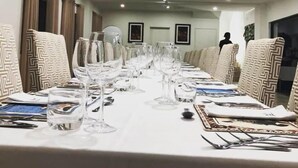 Ein Konferenzraum mit langem Tisch, gedeckt für eine Besprechung, ausgestattet mit Stühlen, Gläsern und Besteck.