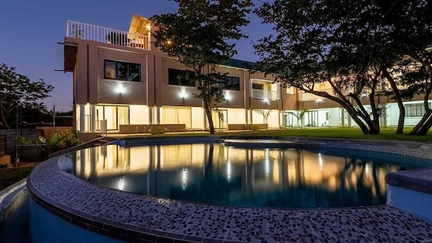 Ein modernes, zweistöckiges Gebäude mit einem Pool im Vordergrund.