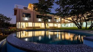 Un bâtiment moderne à deux étages, avec une piscine en premier plan.