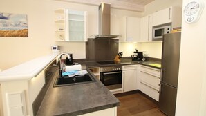Una cocina moderna con armarios blancos, un refrigerador de acero inoxidable, un microondas y una estufa.