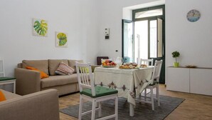 A living room with a sofa, a dining table with chairs, and a kitchen area with a sink and cabinets. - Casa Mariagrazia-Etna House Mare Presa-Piedimonte (Presa)
