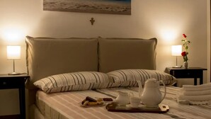 A neatly made bed with striped pillows, a tray with tea and snacks, and a cross on the wall. - Casa Mariagrazia-Etna House Mare Presa-Piedimonte (Presa)