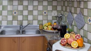 A kitchen with two sinks, a countertop with fruits and a bottle, and a tiled backsplash. - Casa Mariagrazia-Etna House Mare Presa-Piedimonte (Presa)