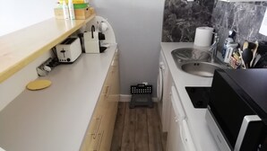 Una cocina compacta con microondas, tostadora y lavamanos.